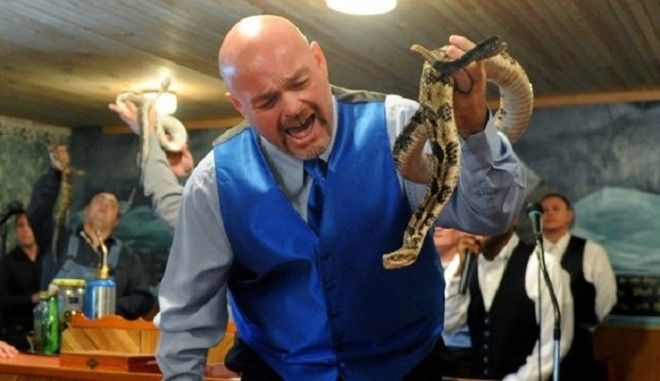 Jamie Coots, pastor of the Full Gospel Tabernacle in Jesus Name Church of Middlesboro, Ky, stands on a bench before the church, singing and holding a rattlesnake during service at Tabernacle Church of God in LaFollette, Tenn on May 6, 2012. Coots has been handling snakes in his KY church for more than 20 years. (Photo by Shelley Mays)