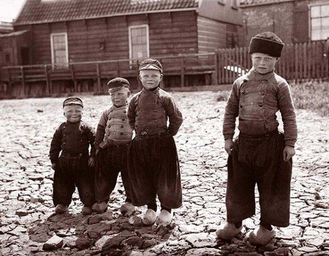 Четыре мальчика в мешковатых штанах рубашках с пуговицами и в деревянных клогах на ногах Волендам Нидерланды